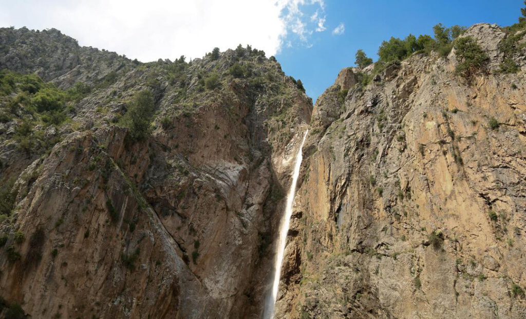 Hoher Wasserfall zwischen steilen Felsen im Arslanbob-Gebiet