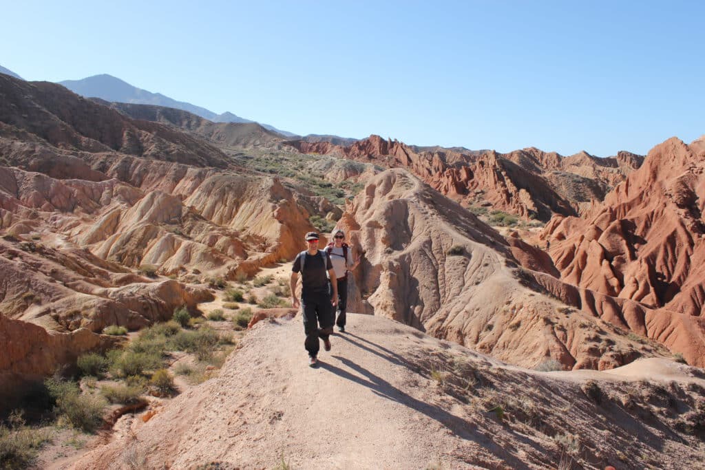 Zwei Wanderer auf sandiger Gratlinie im rotgelben Skazka-Canyon