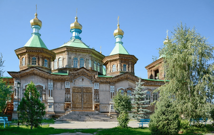 Russisch-orthodoxe Holzkirche in Karakol mit goldenen Zwiebeltürmen im Sonnenschein
