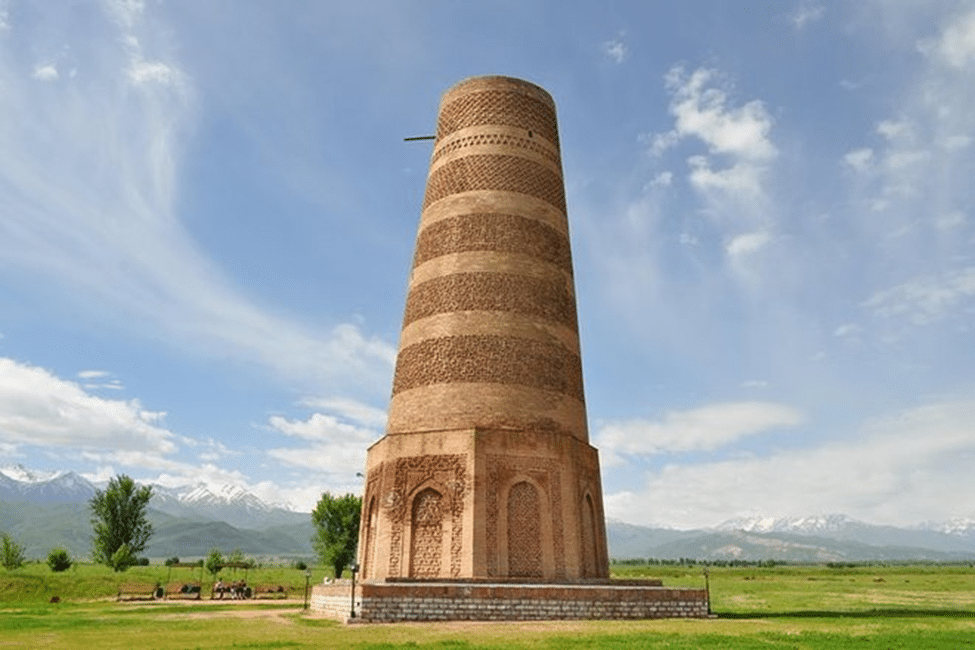 Alter Burana-Turm vor grüner Ebene und schneebedeckten Bergen