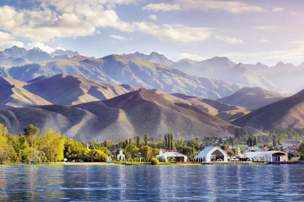 Uferpromenade von Cholpon Ata am Issyk-Kul-See vor sanften, sonnenbeschienenen Bergen